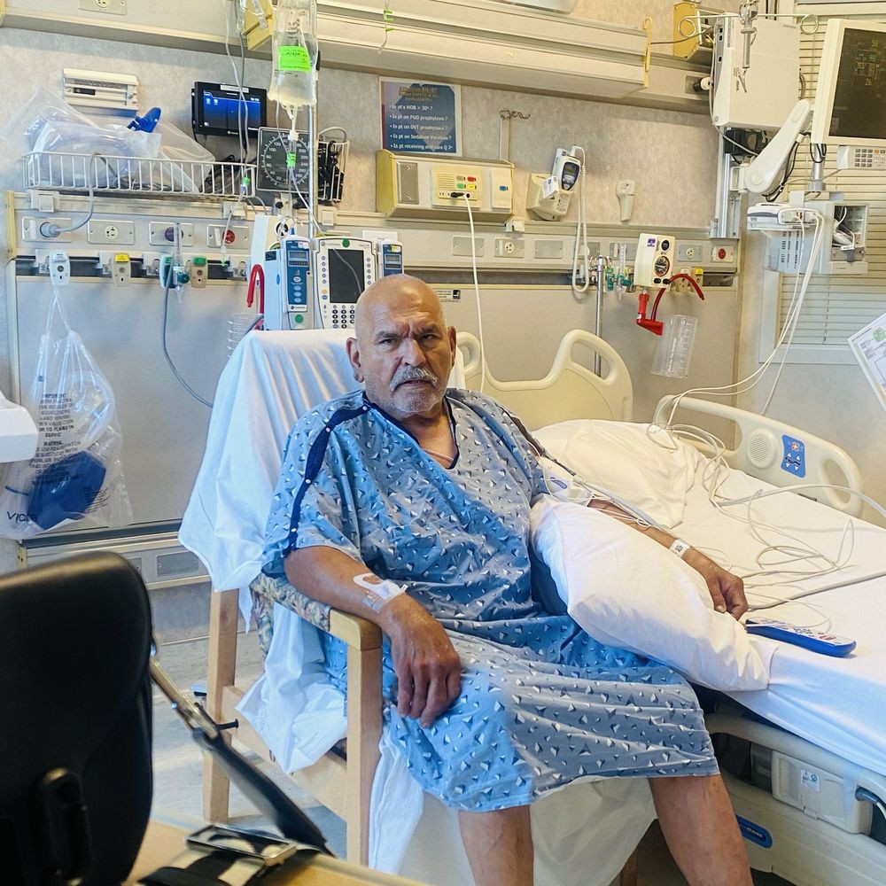 A patient sitting in a hospital room surrounded by medical equipment.