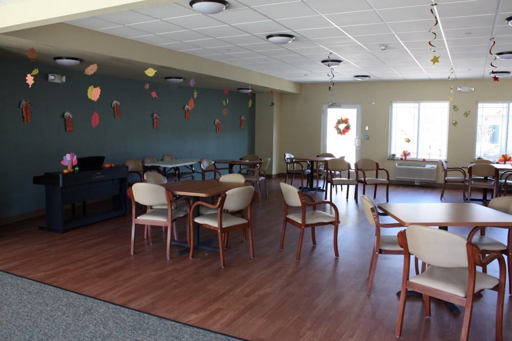 An empty community room with tables and chairs, decorated with hanging ornaments.