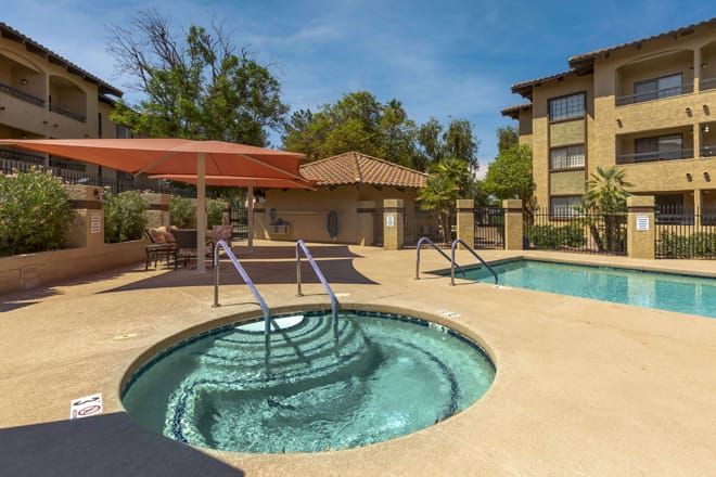 A relaxing outdoor area featuring a hot tub and pool at an apartment complex on a sunny day.