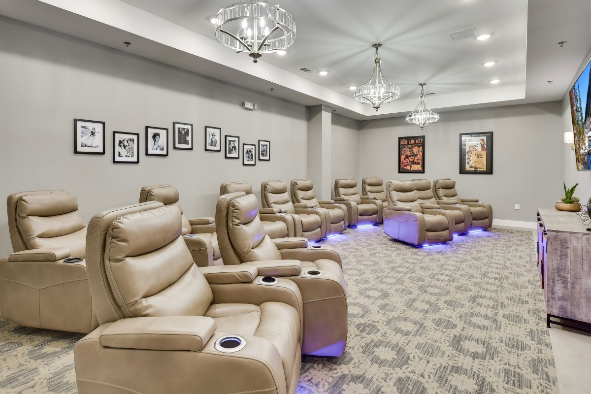 A modern home theater with recliner seating and elegant lighting fixtures.