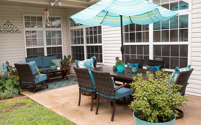 A cozy backyard patio with comfortable seating and a large umbrella.