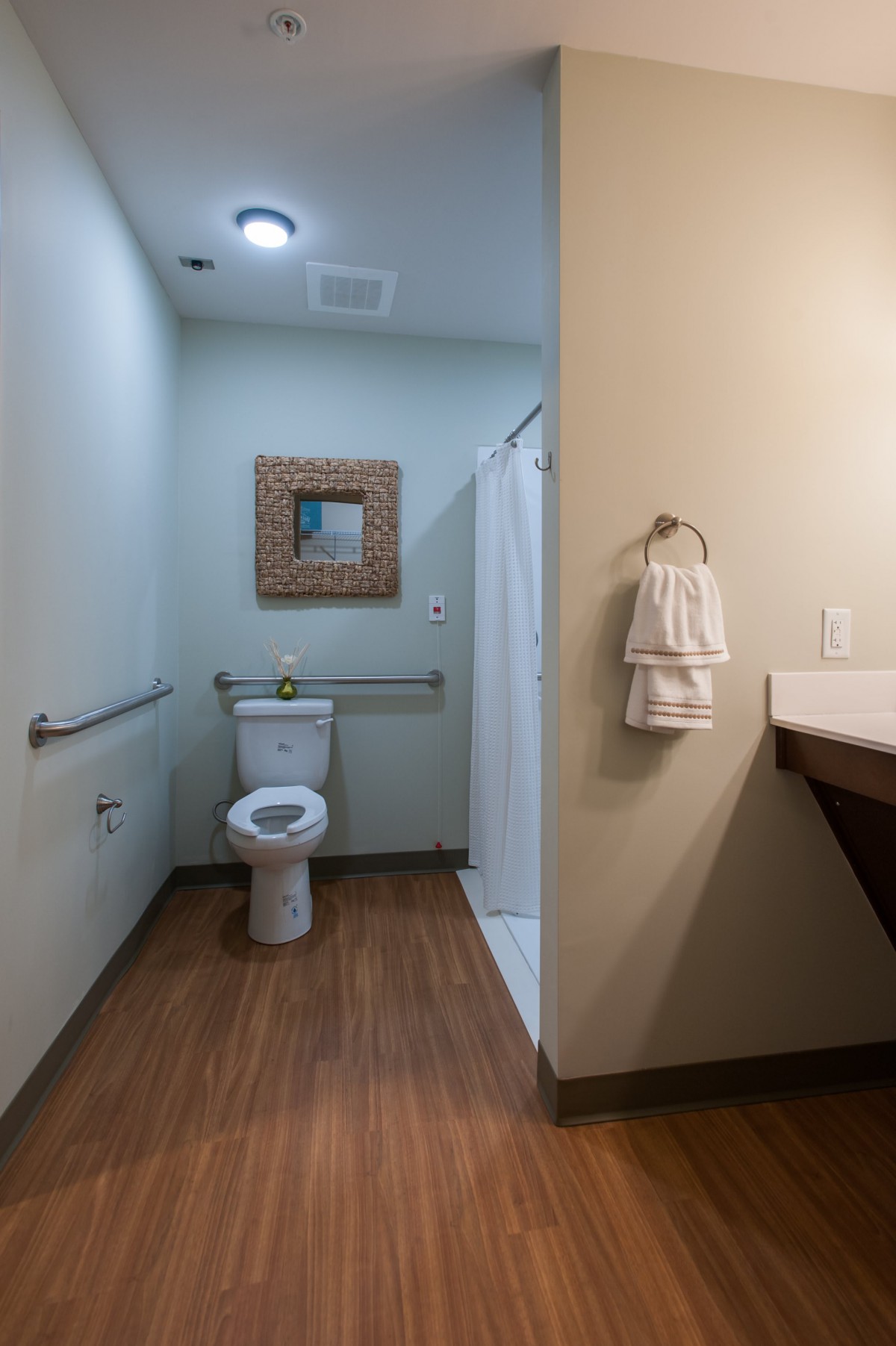 A clean and modern bathroom with a toilet, mirror, shower, and towels.