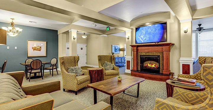 A cozy living room interior with a fireplace, seating area, and television.