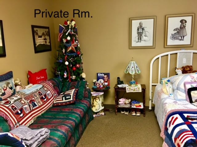 A cozy private room decorated with Christmas ornaments, featuring a couch, bed, and a lit lamp.