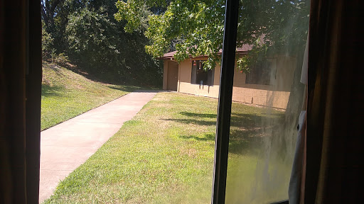 A peaceful view of a building surrounded by greenery and a walkway leading up to it.