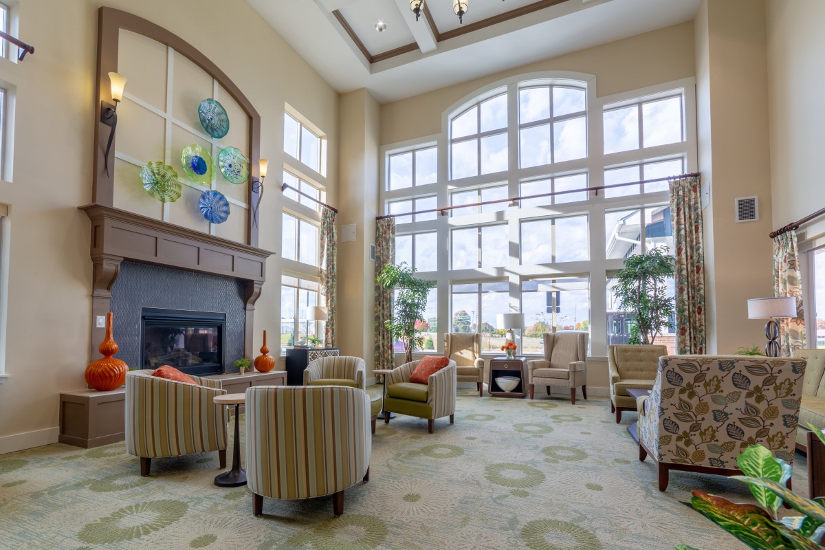 A spacious and well-lit lounge area featuring comfortable seating, large windows, and a cozy fireplace.