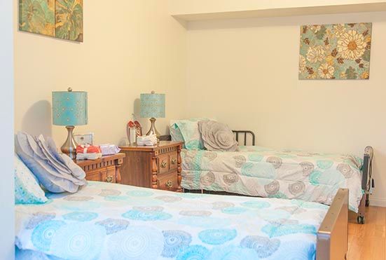 A cozy bedroom with twin beds and matching bedspreads, featuring decorative lamps on the nightstands.