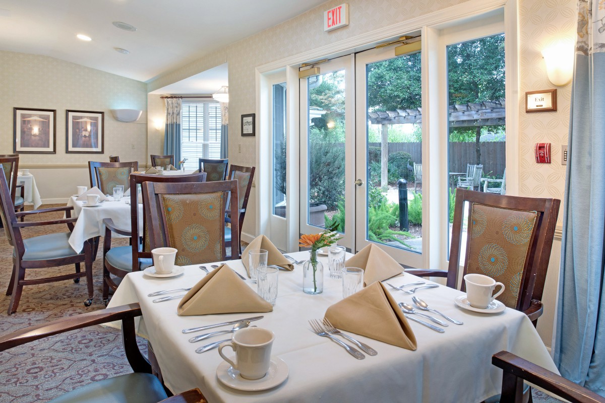A well-set dining area with neatly arranged tables and chairs by large windows.