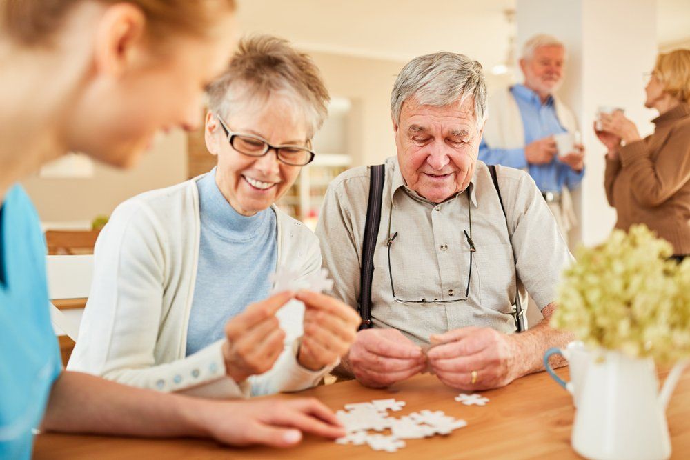 Two elderly people enjoy working on a puzzle together indoors.