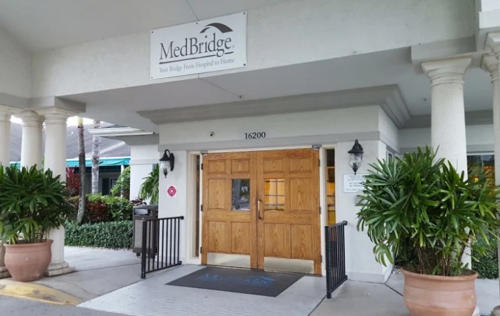 Entrance to a healthcare facility with wooden double doors and a sign above.