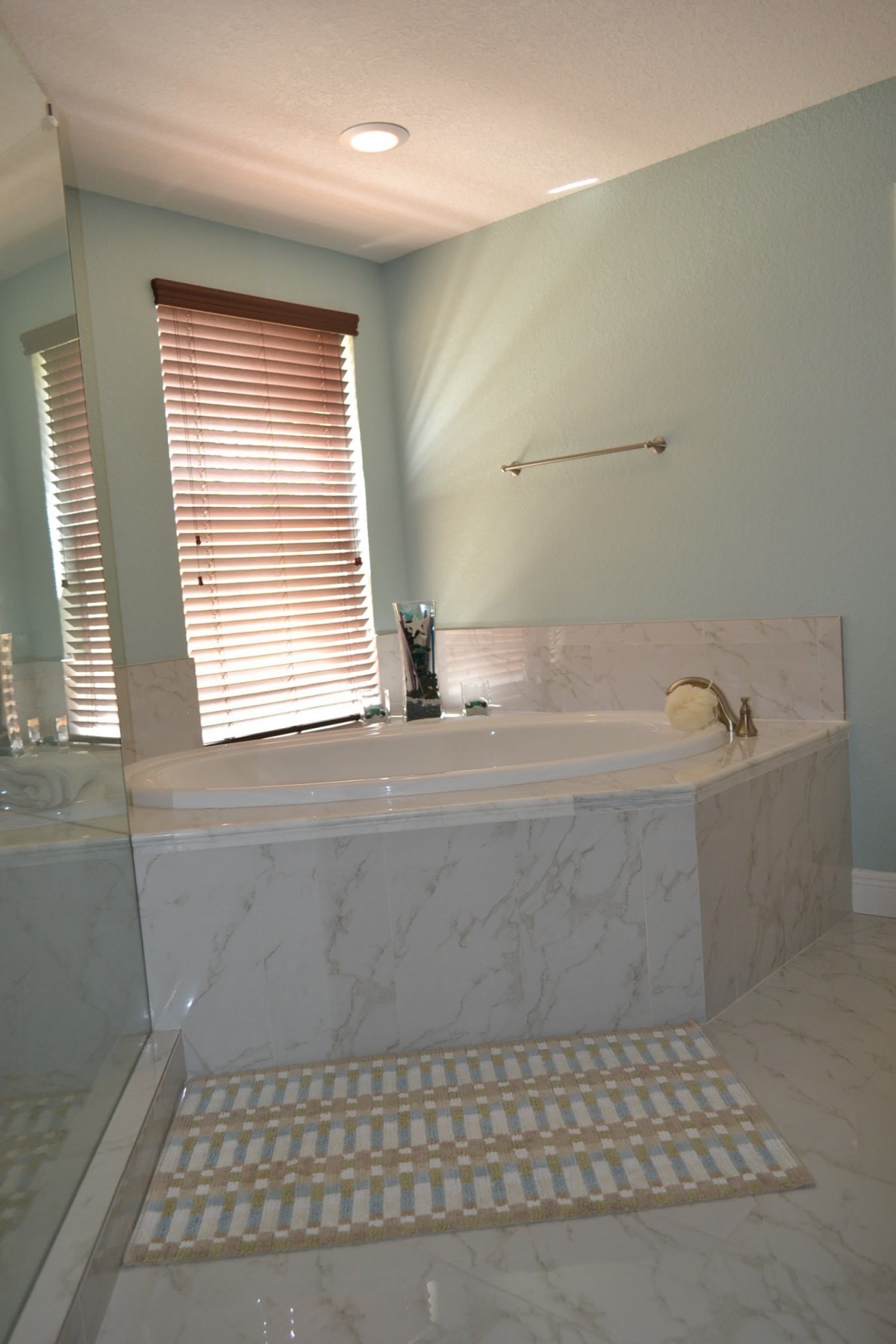 A bathroom with a corner bathtub and window blinds.