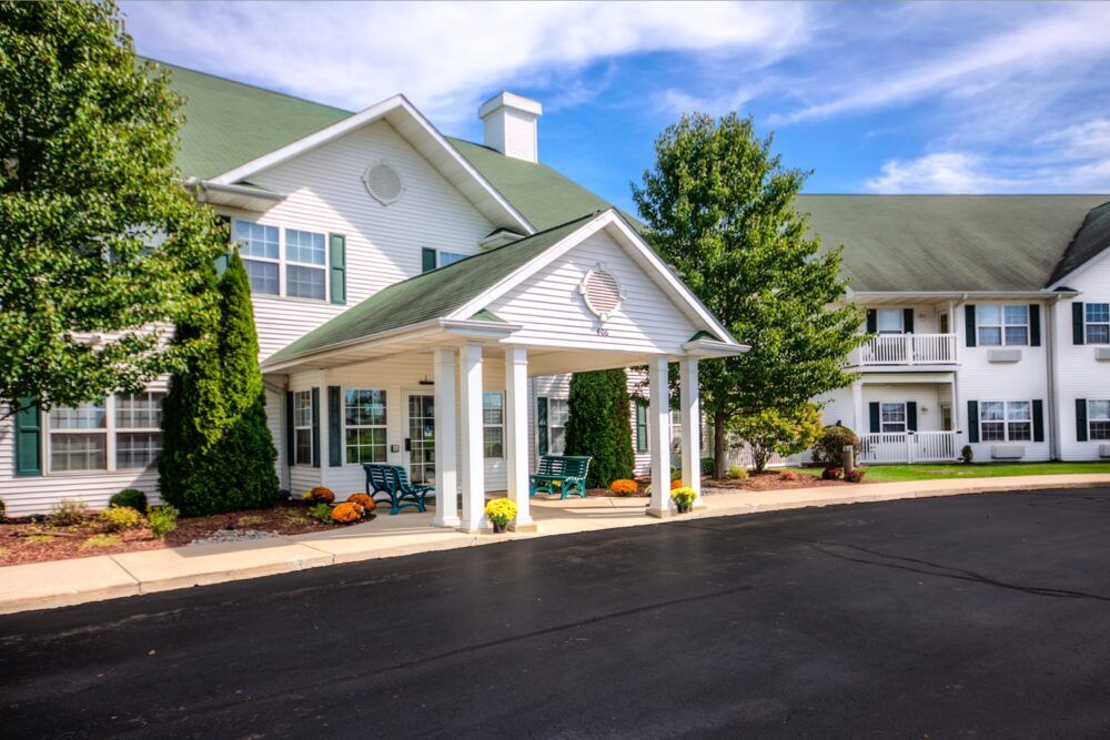A charming residential building with a welcoming porch and well-maintained landscaping under a bright blue sky.