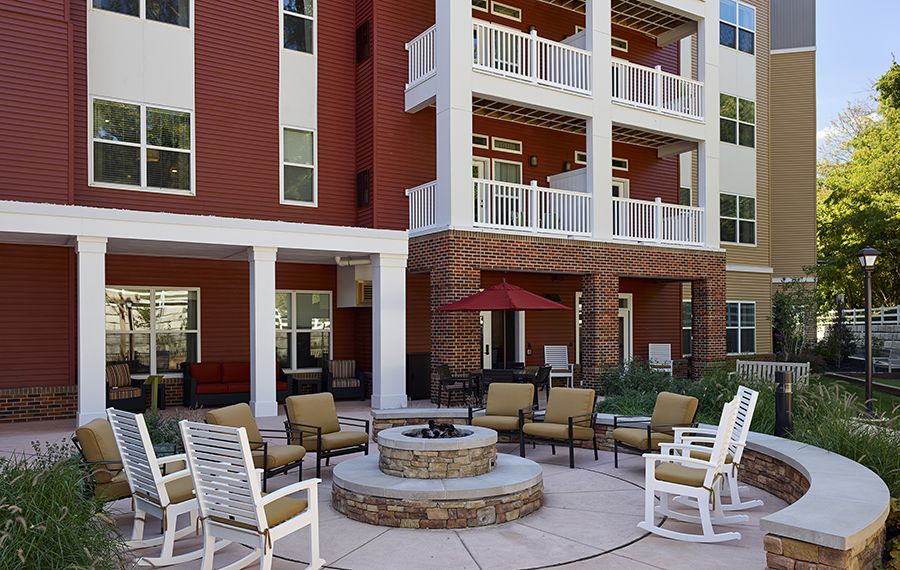 A cozy outdoor patio area with a fire pit and comfortable seating outside an apartment building.
