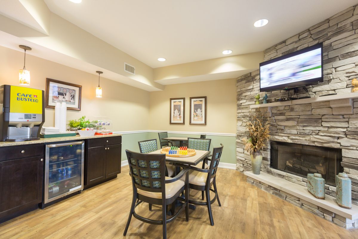 A cozy dining area with a table and chairs, featuring a stone fireplace and a television mounted above.
