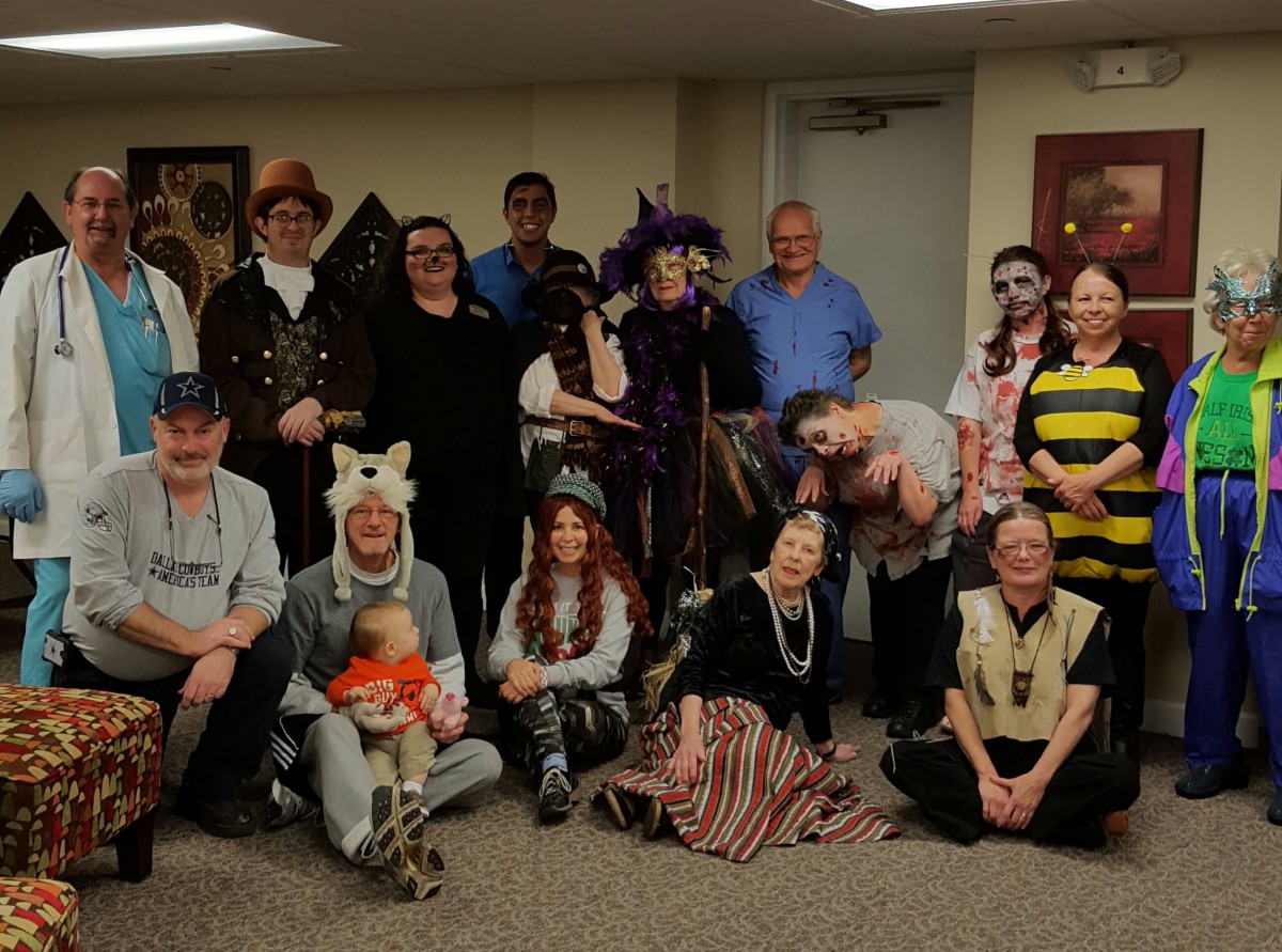A group of people dressed in various costumes, posing indoors for a festive Halloween photo.