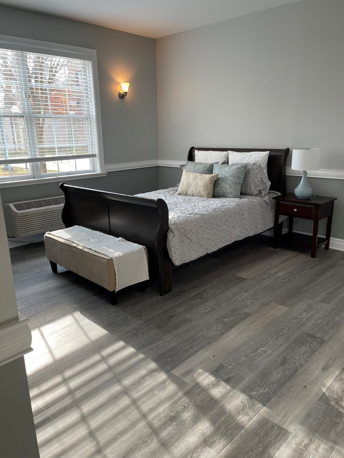 A cozy bedroom with a wooden bed and ample natural light.