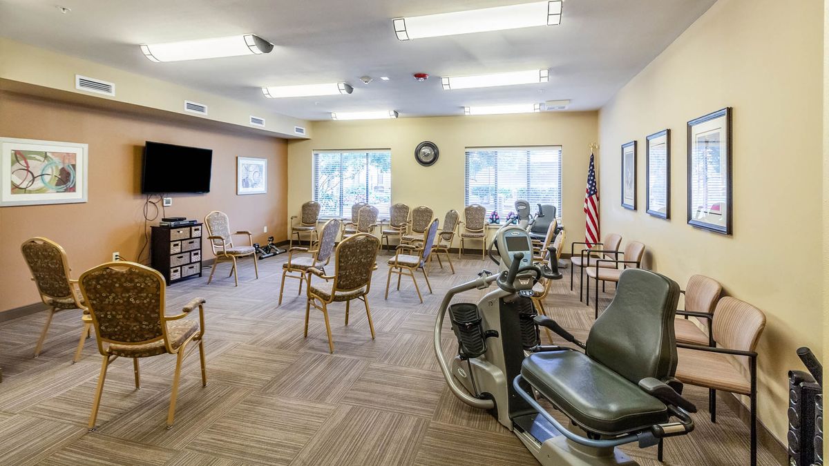 A spacious exercise room equipped with fitness machines and arranged chairs, suitable for group activities in a healthcare facility.