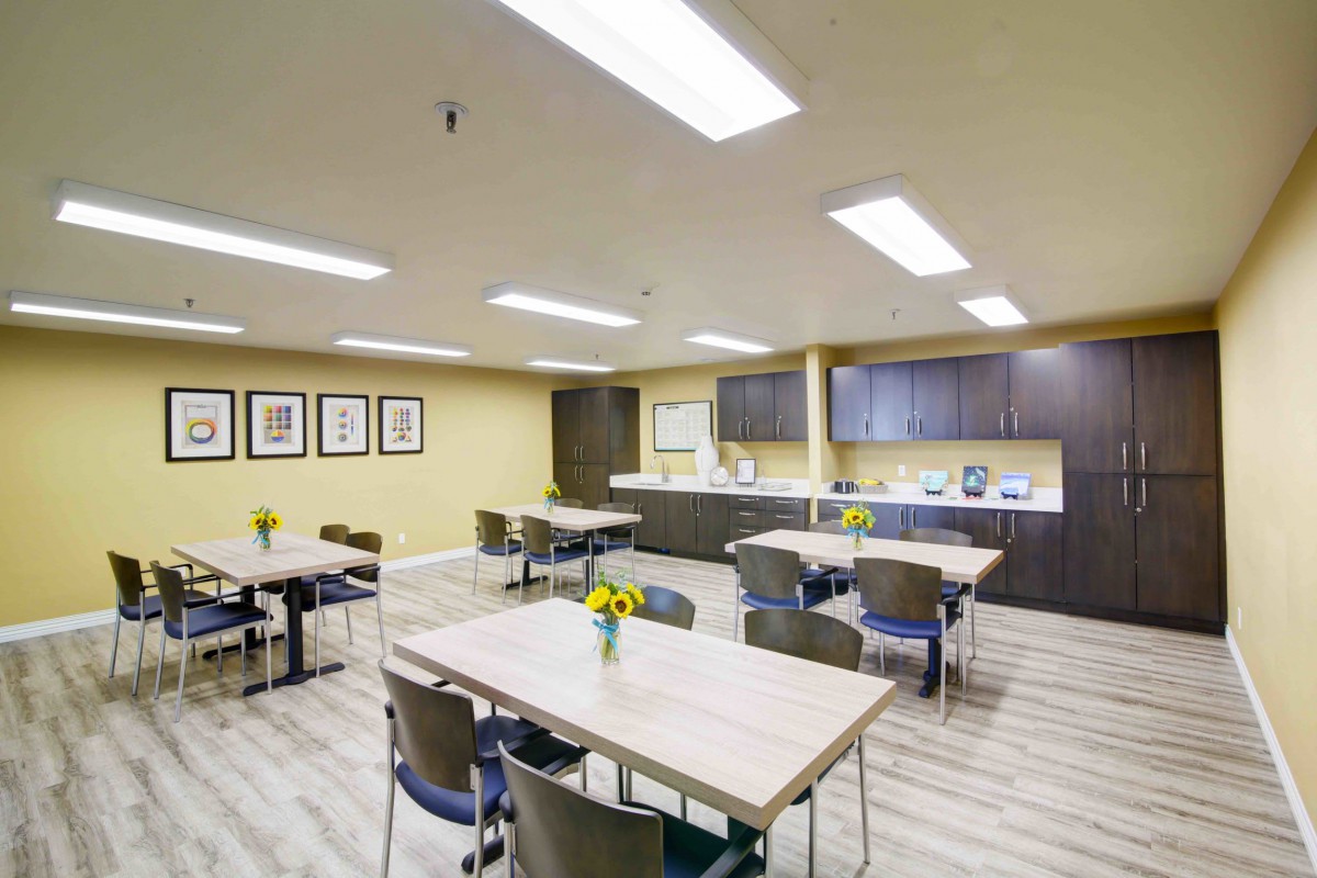 A modern conference room with tables and chairs, featuring a sleek design and bright fluorescent lighting.