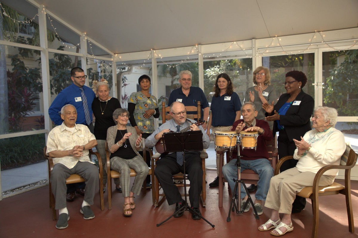 A group of people gathered indoors, some seated and playing musical instruments, creating a lively and festive atmosphere.
