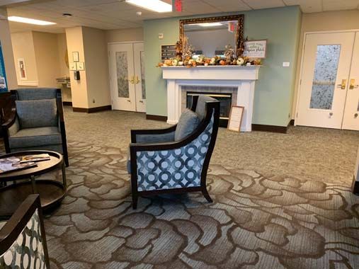 A cozy lobby area with a patterned chair and a decorated fireplace.
