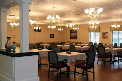 A spacious dining room featuring elegant chandeliers and set tables.