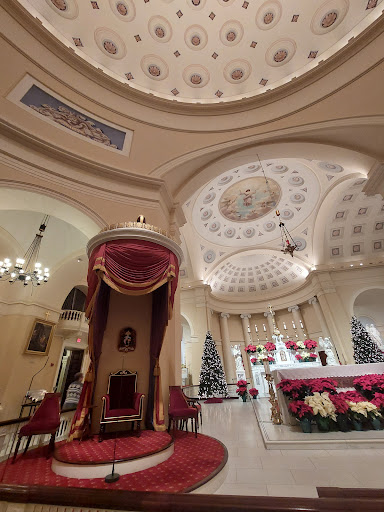 A beautifully decorated church interior featuring an ornate ceiling and a throne, set for the Christmas season.