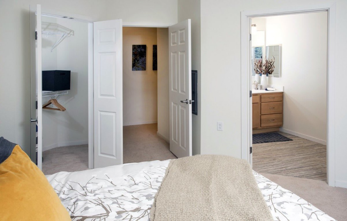 A modern bedroom with an open view into a bathroom and hallway.