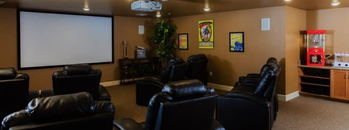 A cozy home theater with leather recliners and movie posters on the wall.