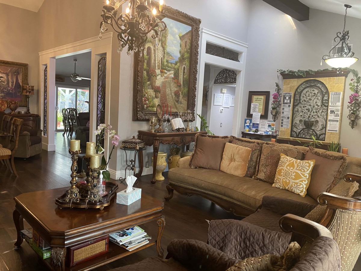 A cozy living room with elegant furnishings, featuring a classic sofa, artwork on the walls, and a chandelier illuminating the space.