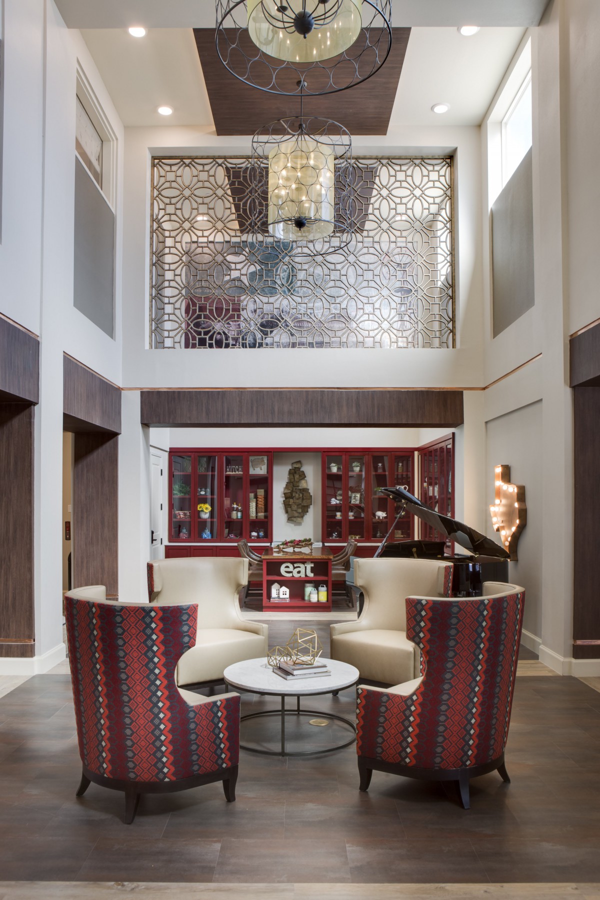 A luxurious living room with modern furniture, featuring a chandelier and intricate wall decor.