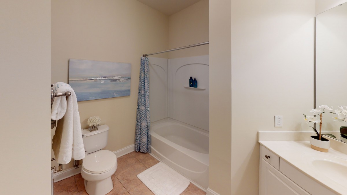A neatly organized bathroom with a bathtub and shower curtain, toilet, and sink.