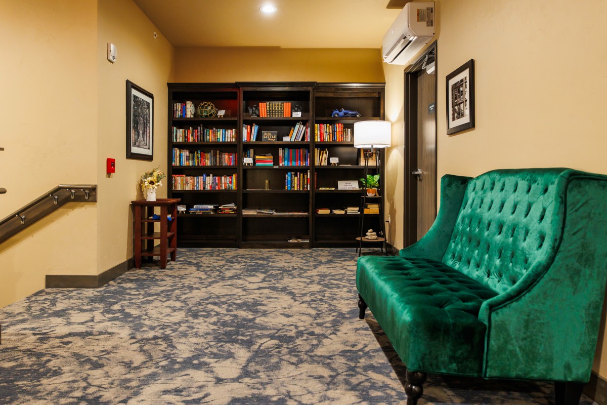 Cozy library space with a green sofa and a well-stocked bookshelf.