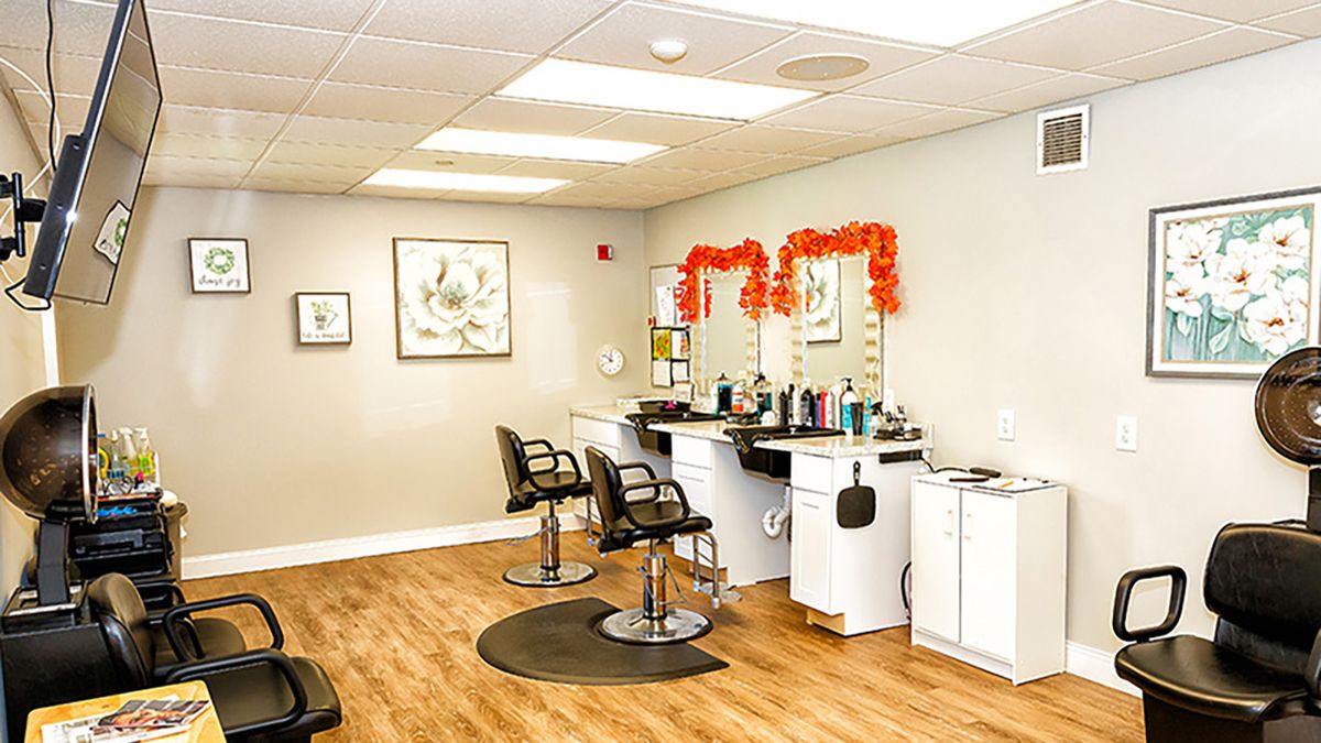 A bright and clean hair salon interior with two styling chairs, mirrors, and various hair products.