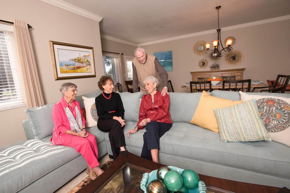A group of elderly individuals sitting and conversing in a cozy living room setting.