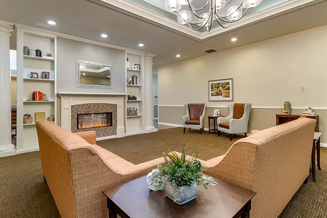 A cozy living room with a fireplace, armchairs, and a sofa, featuring elegant interior design elements.