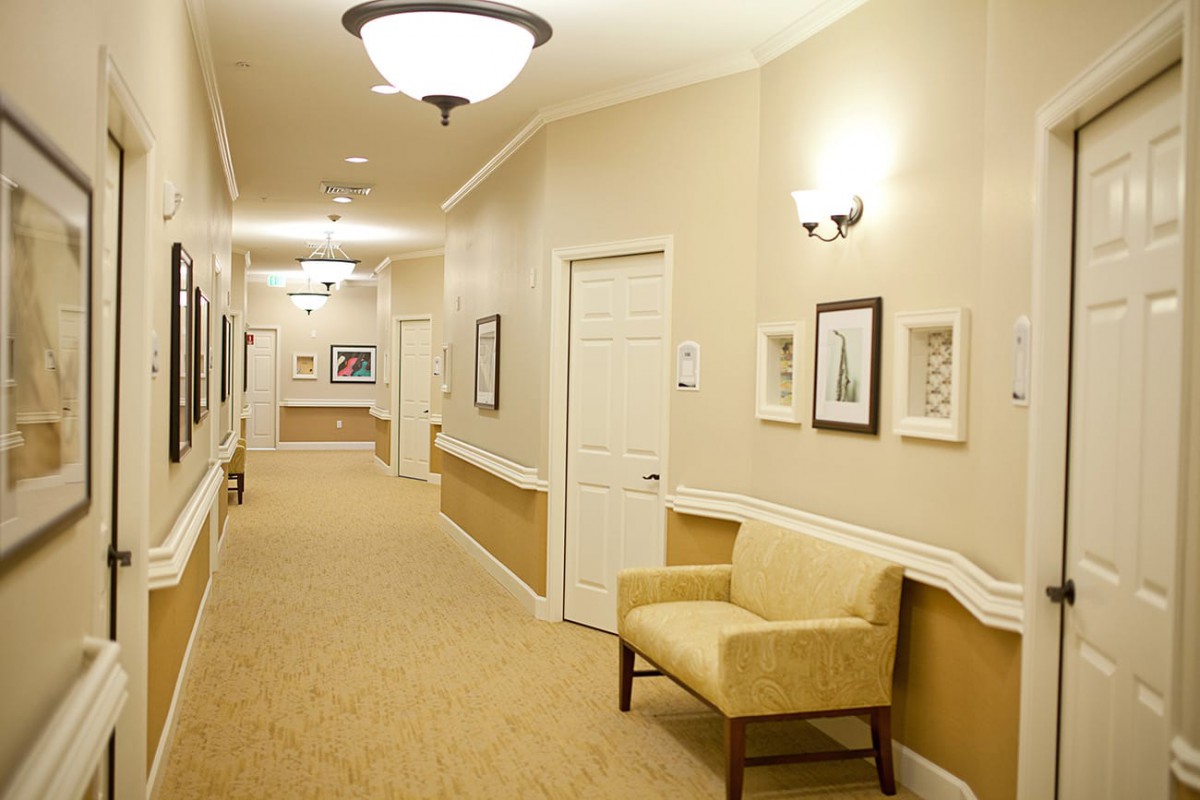 A well-lit hallway with a chair and framed pictures on the walls.