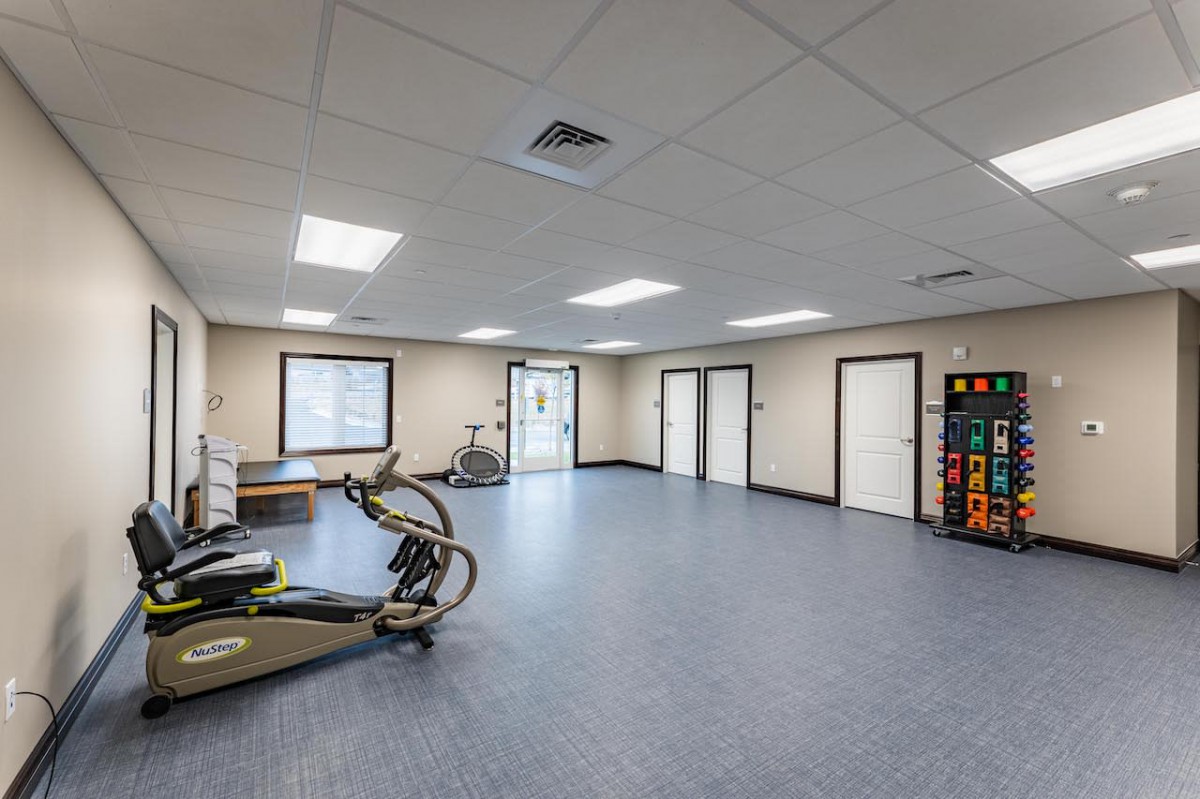 A spacious gym area with exercise and cardio equipment.