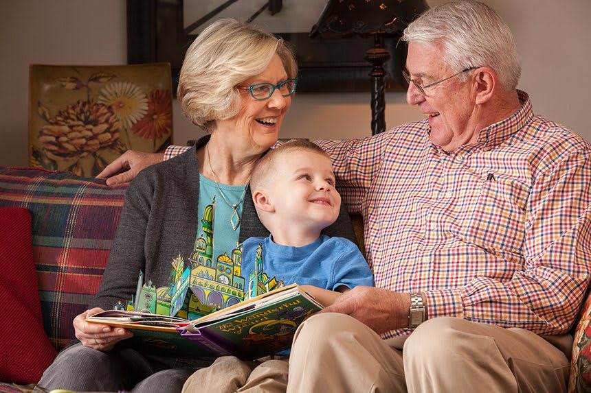 A happy moment as grandparents read a book with their young grandchild.