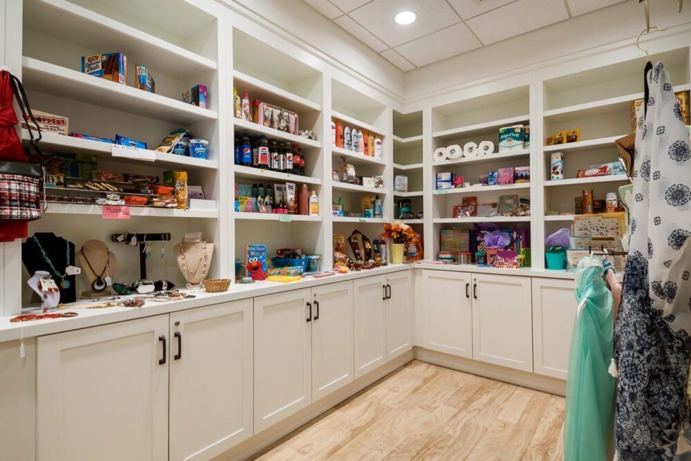 A well-organized pantry with white shelves and cabinets full of assorted kitchen items.
