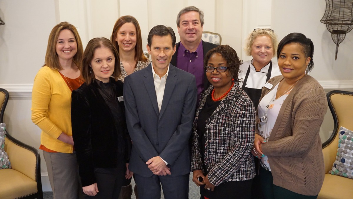 A group of people posing together in business attire, smiling for the camera.