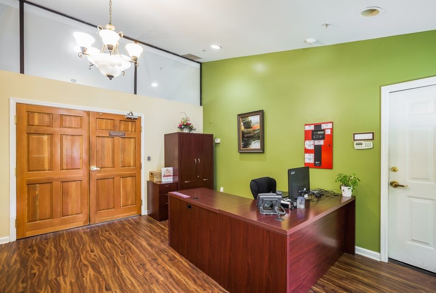 A well-lit office reception area featuring a desk, computer, and artwork on a green wall.