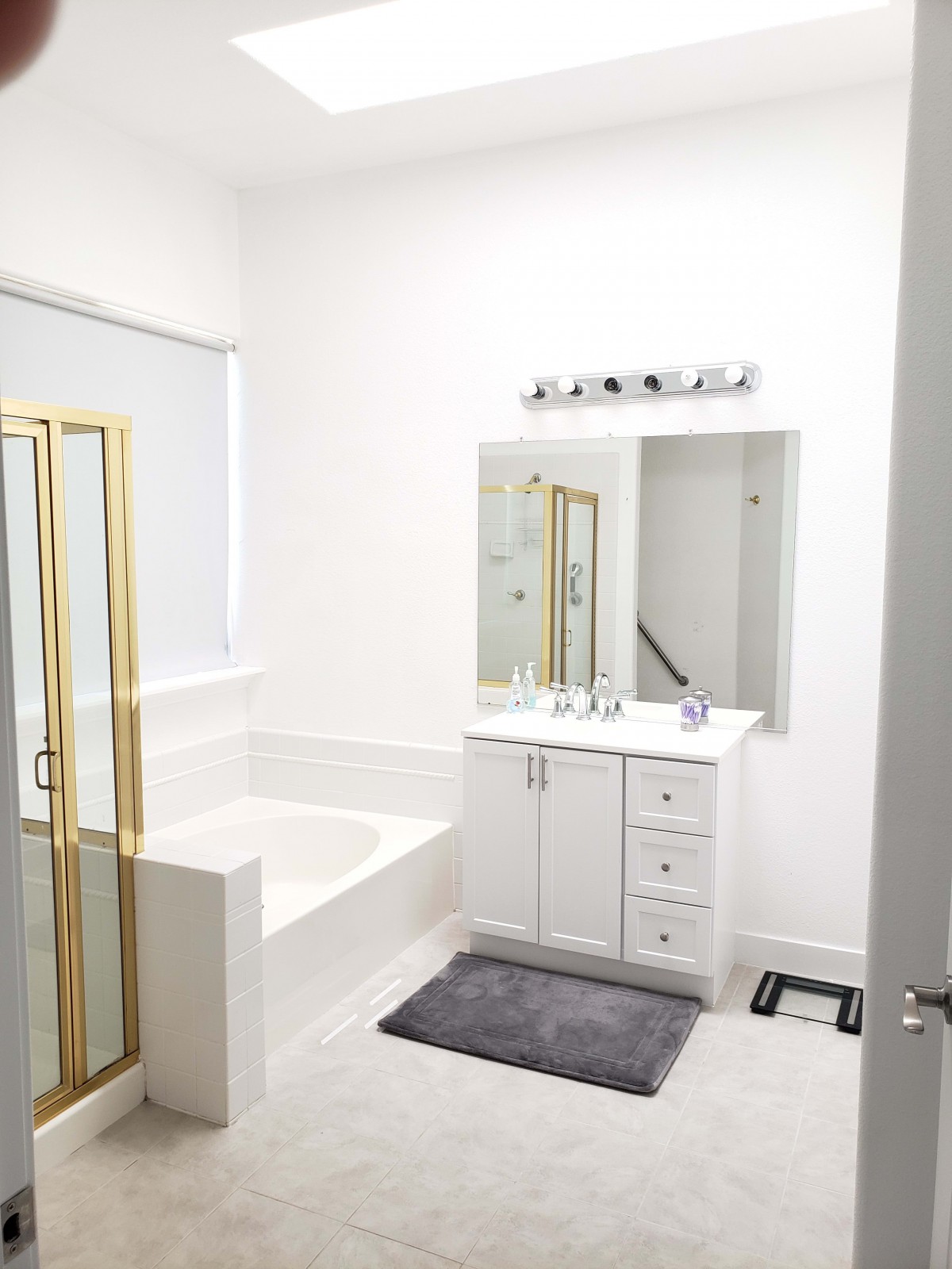 A modern bathroom with a bathtub, shower, and vanity featuring a large mirror.