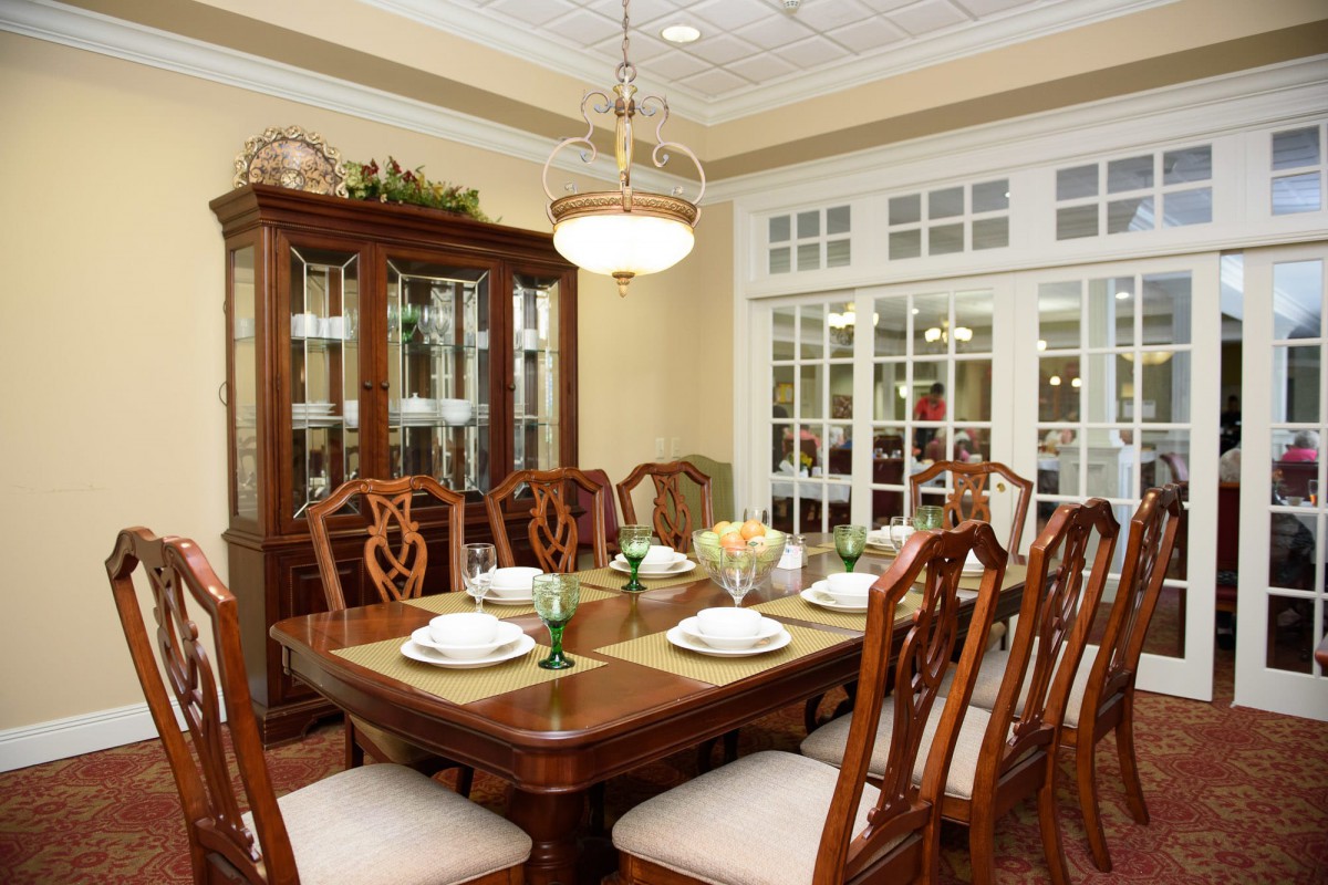 An elegant dining room with a wooden table and chairs, complemented by a chandelier.