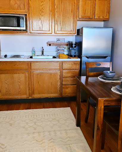 A cozy kitchen featuring wooden cabinets, modern appliances, and a small dining area.