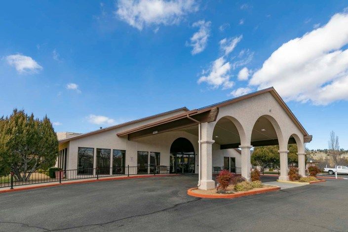 Exterior view of a hotel with arched entrance under a clear blue sky.