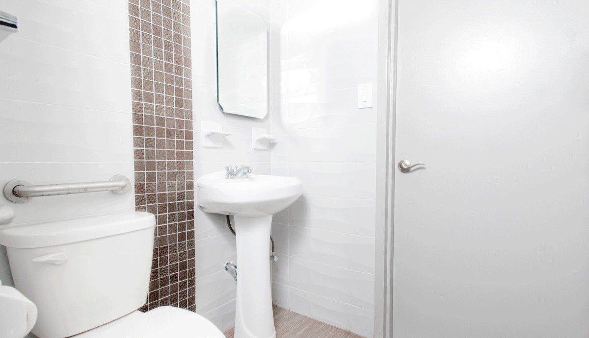A clean, modern bathroom with a pedestal sink and tiled wall.