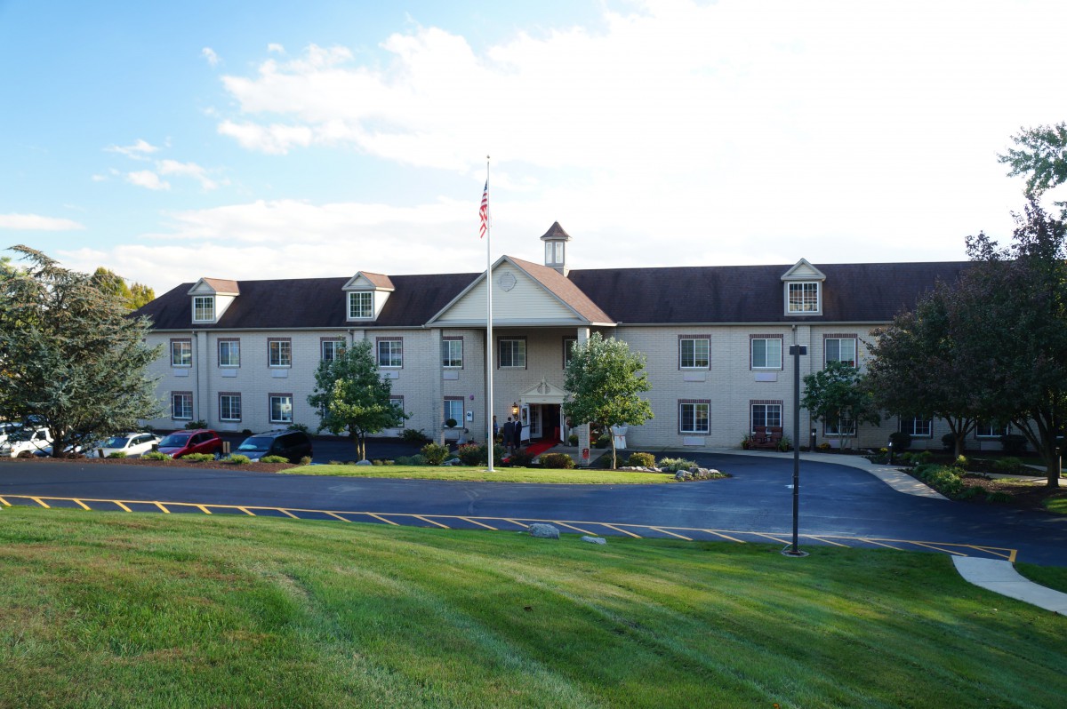 A hotel building with a well-kept lawn and a parking lot in front.