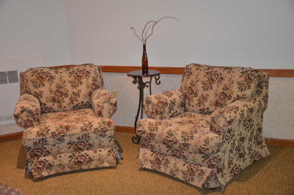 A pair of vintage-style upholstered chairs with a patterned fabric, accompanied by a decorative side table.