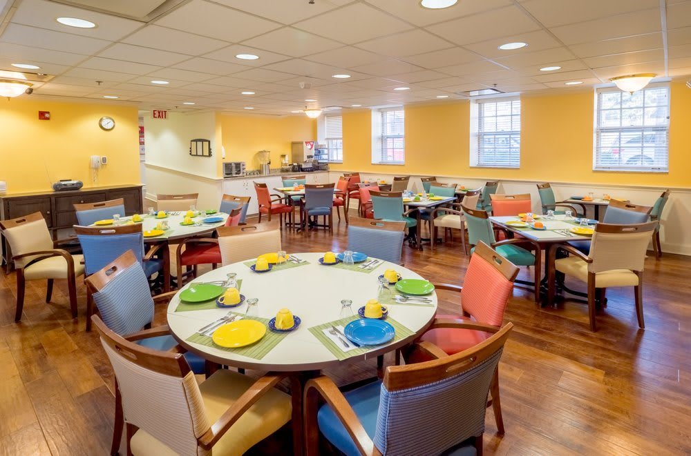 A brightly colored dining room with neatly set tables and chairs, ready for guests.