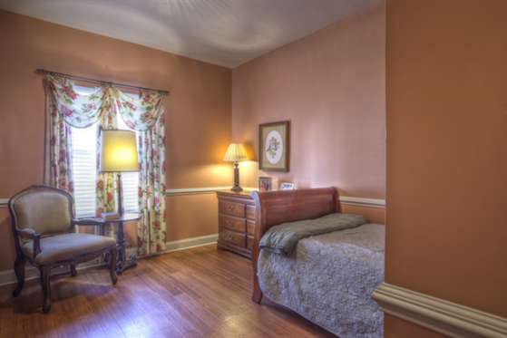 A cozy bedroom with traditional decor, featuring a wooden floor, bed, and warm lighting from lamps.